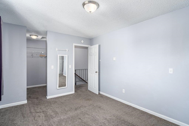 12409 E Olive Ave, Spokane Valley, WA 99216 - unfurnished bedroom with carpet floors, a closet, a textured ceiling, baseboards, and a walk in closet