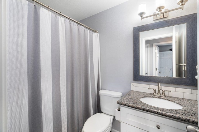 bathroom with vanity, toilet, and decorative backsplash