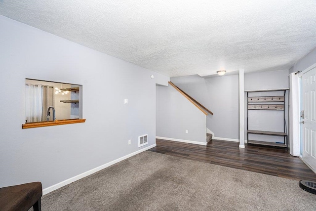 unfurnished living room with sink, dark carpet, and a textured ceiling