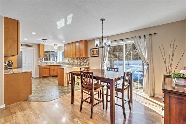 dining room with an inviting chandelier, sink, light hardwood / wood-style floors, and a textured ceiling