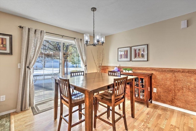 dining space with a chandelier, a textured ceiling, and light hardwood / wood-style floors