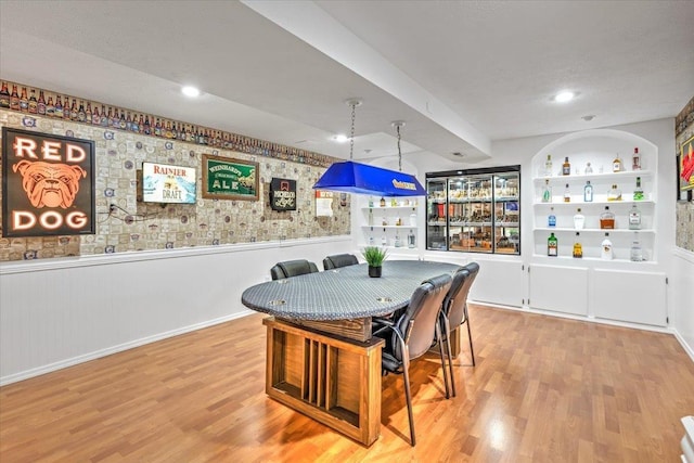 dining space with built in shelves and light hardwood / wood-style floors