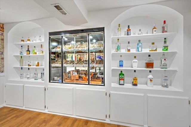 bar featuring built in shelves and light hardwood / wood-style flooring