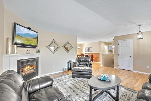 living room with hardwood / wood-style floors, vaulted ceiling, and a textured ceiling