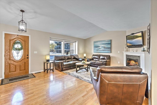 living room featuring vaulted ceiling and light hardwood / wood-style flooring