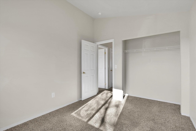 unfurnished bedroom with carpet flooring, vaulted ceiling, and a closet