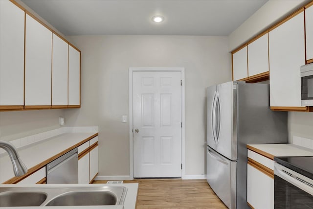 kitchen featuring white cabinetry, sink, light hardwood / wood-style floors, and appliances with stainless steel finishes