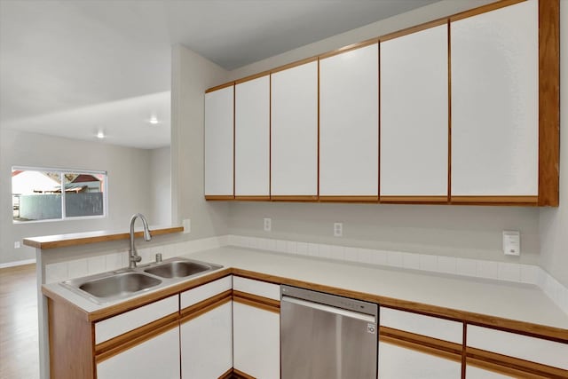 kitchen featuring sink, light hardwood / wood-style flooring, stainless steel dishwasher, kitchen peninsula, and white cabinets