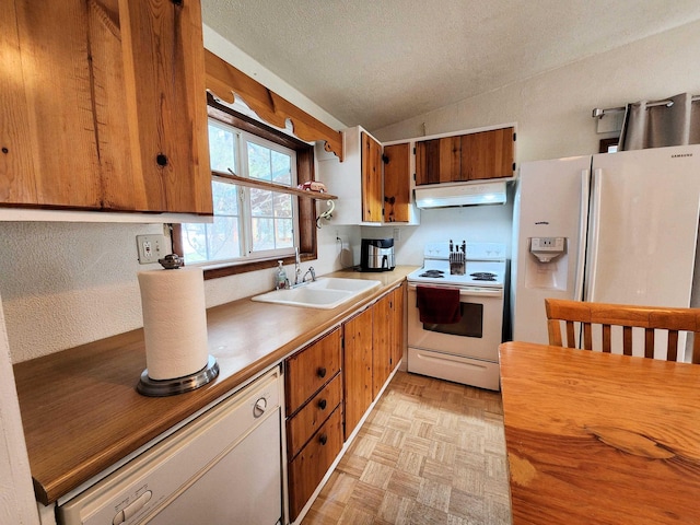 kitchen with lofted ceiling, sink, white appliances, light parquet floors, and a textured ceiling