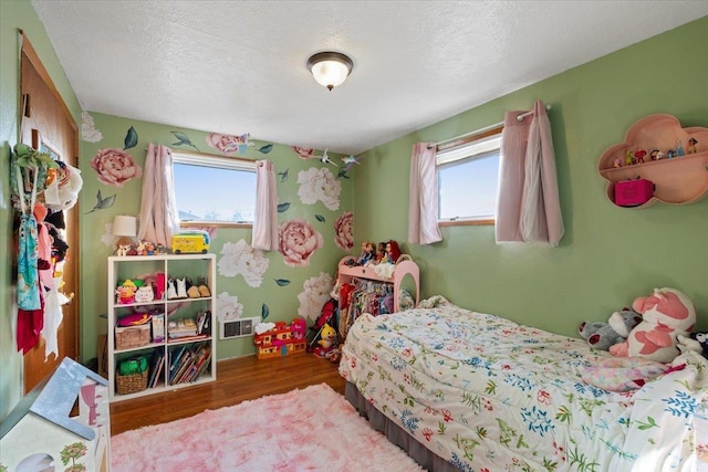 bedroom featuring multiple windows, hardwood / wood-style flooring, and a textured ceiling