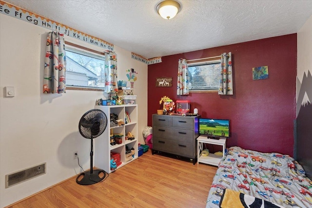 bedroom with a textured ceiling and light hardwood / wood-style floors