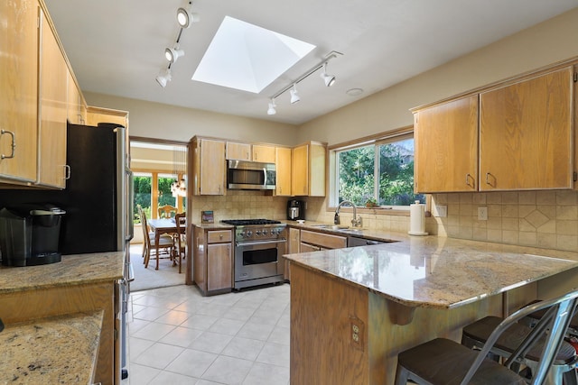 kitchen featuring appliances with stainless steel finishes, sink, light stone counters, and kitchen peninsula