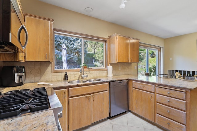 kitchen with sink, light tile patterned floors, kitchen peninsula, stainless steel appliances, and decorative backsplash