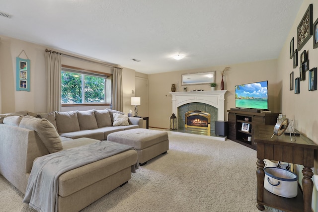 carpeted living room featuring a tile fireplace and a textured ceiling