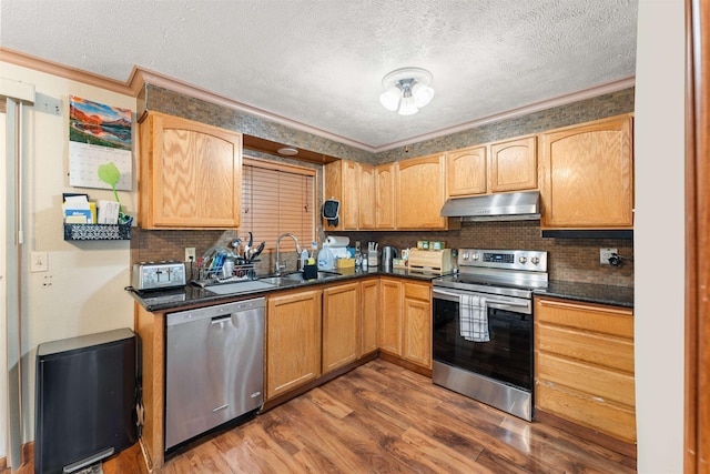 kitchen featuring sink, appliances with stainless steel finishes, a textured ceiling, dark hardwood / wood-style flooring, and decorative backsplash