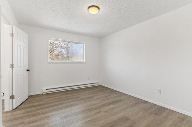 unfurnished room featuring a baseboard heating unit, wood-type flooring, and a textured ceiling