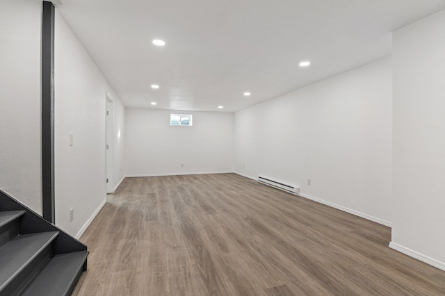 basement featuring a baseboard heating unit and hardwood / wood-style floors