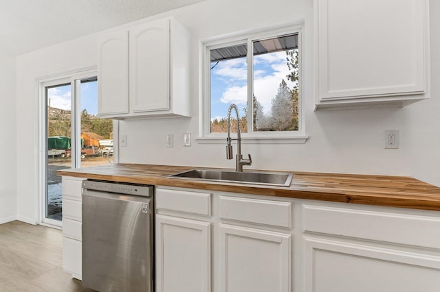 kitchen featuring white cabinetry, sink, stainless steel dishwasher, and butcher block counters