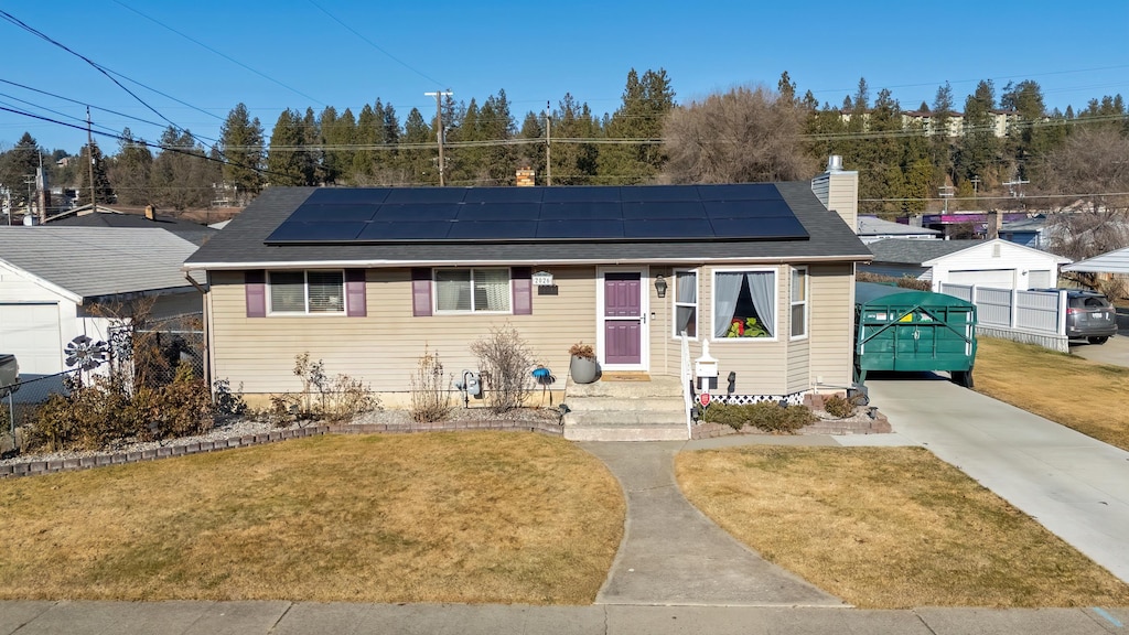 bungalow with a front yard and solar panels