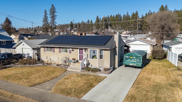 bungalow-style home with a garage, a front yard, and solar panels