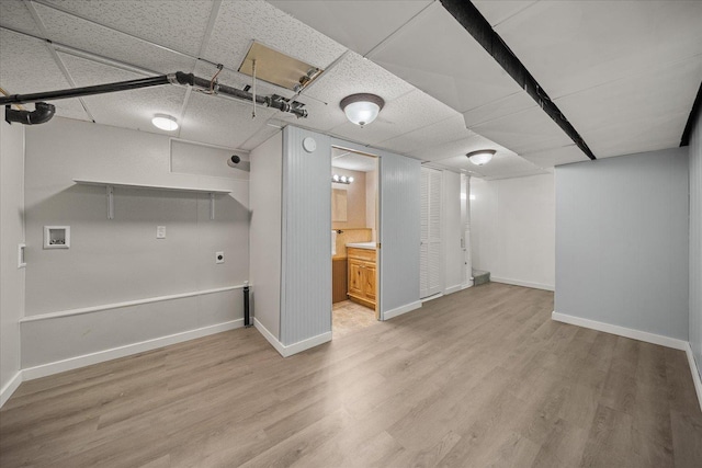 basement with a drop ceiling and light hardwood / wood-style floors