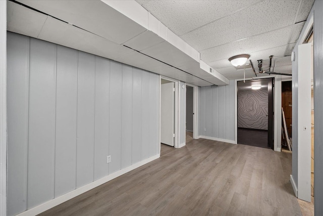 basement featuring a paneled ceiling and light wood-type flooring