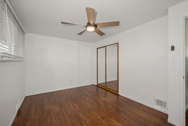 empty room with ceiling fan and dark hardwood / wood-style flooring