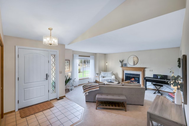 carpeted entrance foyer featuring an inviting chandelier, lofted ceiling, and a tile fireplace