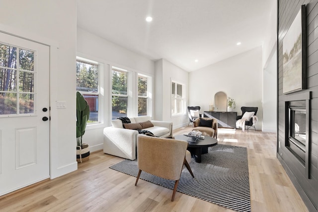 living room with high vaulted ceiling, a fireplace, and light hardwood / wood-style floors