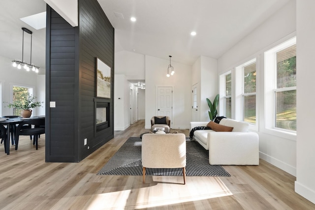 living room with light hardwood / wood-style flooring, a fireplace, and high vaulted ceiling