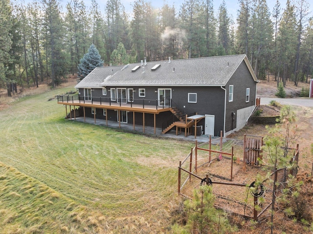 rear view of property with a wooden deck and a lawn