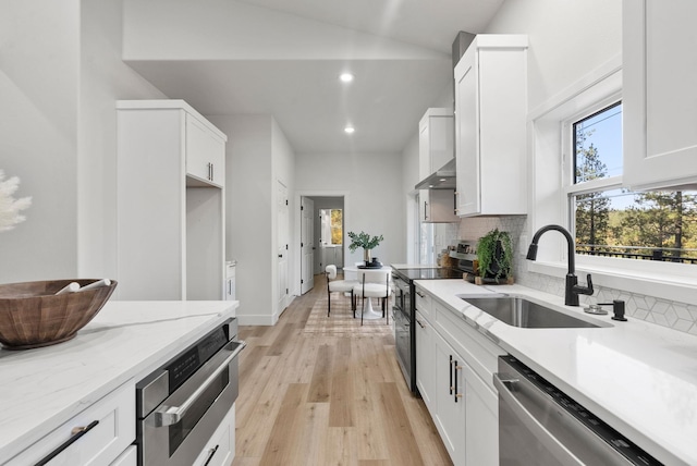 kitchen featuring appliances with stainless steel finishes, sink, white cabinets, decorative backsplash, and light stone countertops