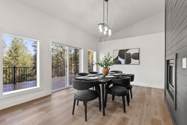 dining space with high vaulted ceiling, plenty of natural light, and light hardwood / wood-style floors