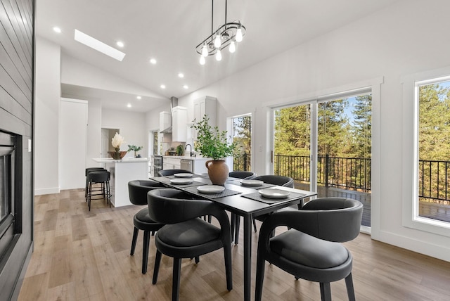 dining area featuring high vaulted ceiling, light hardwood / wood-style floors, and a skylight