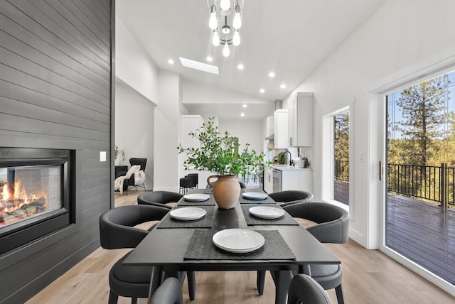 dining room featuring high vaulted ceiling and light hardwood / wood-style floors