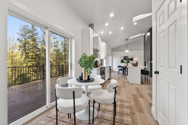 dining area featuring sink, light hardwood / wood-style flooring, and high vaulted ceiling