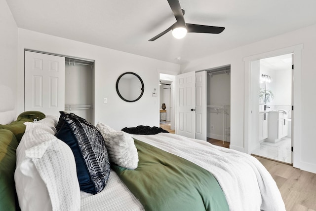 bedroom with multiple closets, ceiling fan, ensuite bath, and light hardwood / wood-style flooring