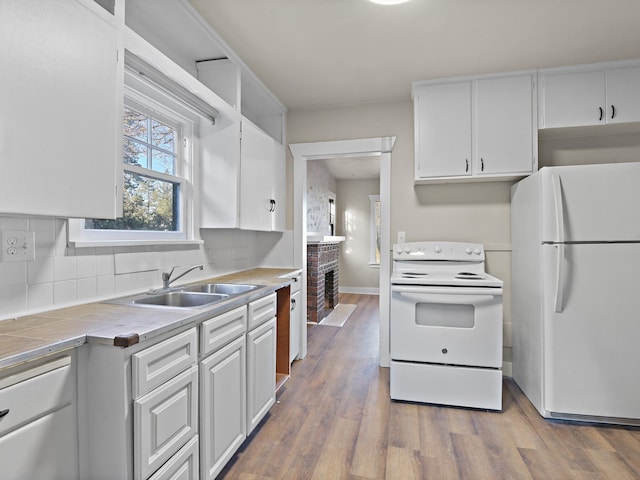 kitchen featuring sink, white cabinetry, tasteful backsplash, wood-type flooring, and white appliances