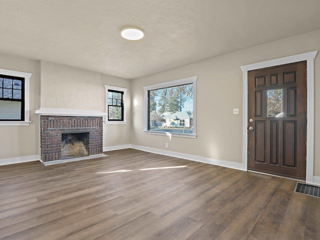 unfurnished living room with a fireplace, dark hardwood / wood-style floors, and a textured ceiling