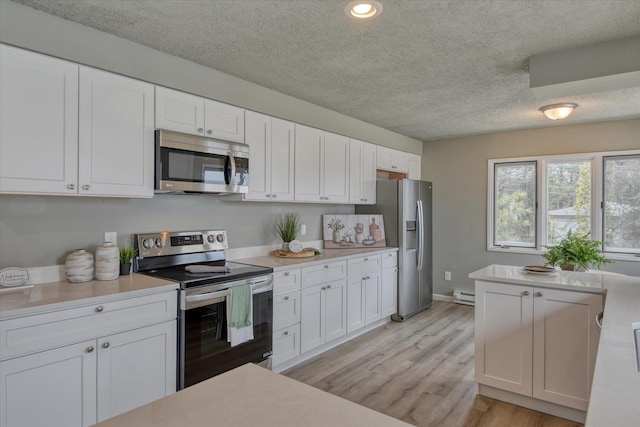 kitchen featuring light countertops, appliances with stainless steel finishes, light wood-type flooring, and white cabinets