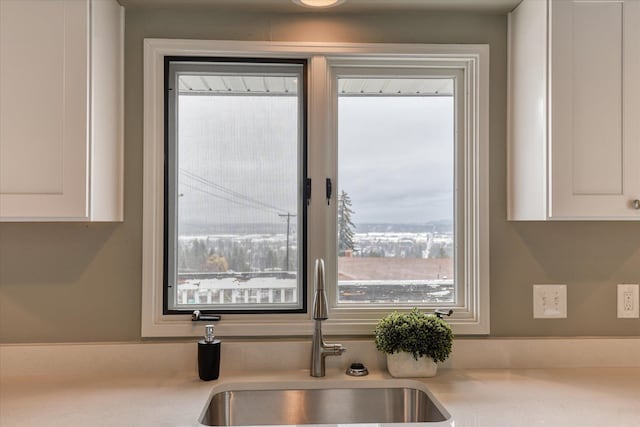 kitchen featuring light countertops, a sink, and white cabinetry