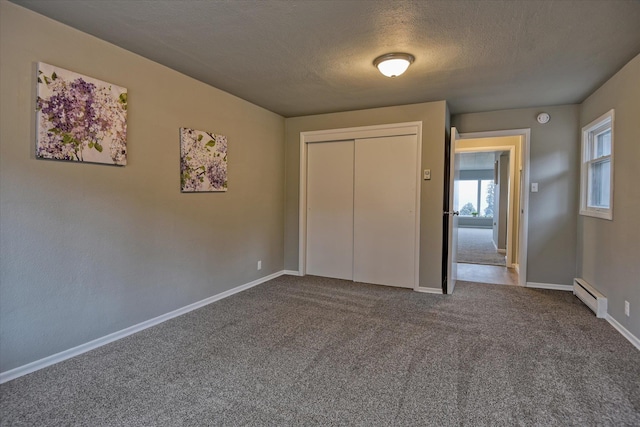 unfurnished bedroom featuring a baseboard heating unit, a textured ceiling, carpet, and a closet