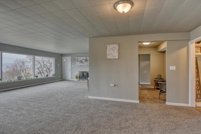 unfurnished living room with baseboards, light colored carpet, and a glass covered fireplace