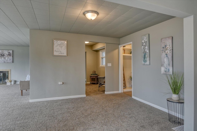 carpeted empty room with visible vents, baseboards, and a glass covered fireplace