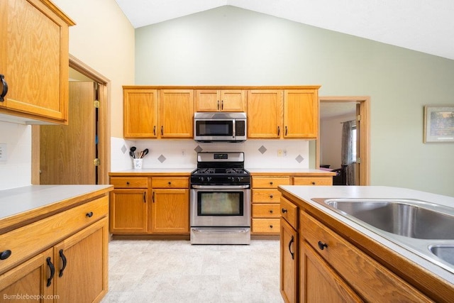 kitchen with tasteful backsplash, lofted ceiling, appliances with stainless steel finishes, and sink