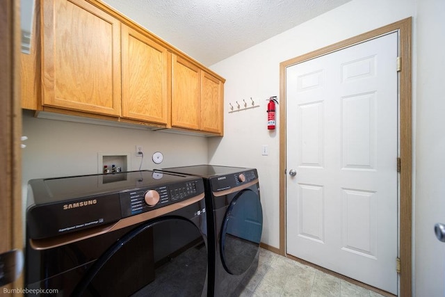 washroom featuring cabinets, washer and clothes dryer, and a textured ceiling