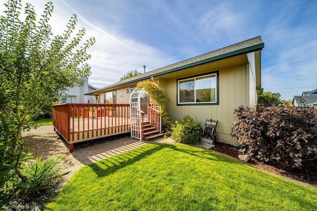 rear view of house with a wooden deck and a yard