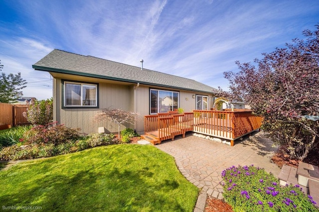 back of property with a wooden deck, a yard, and a patio