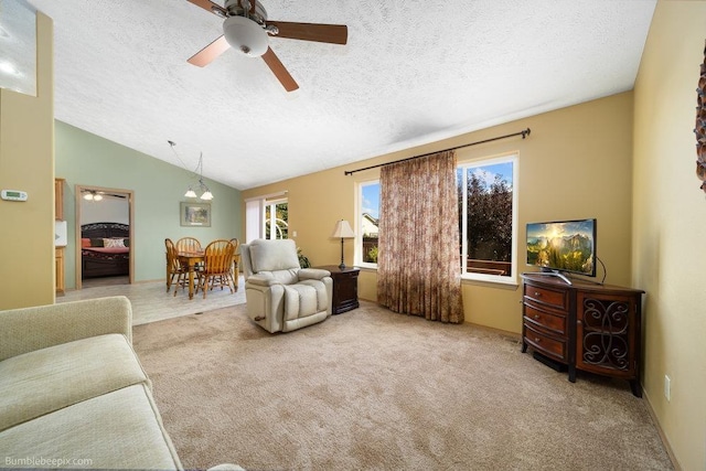 living room featuring ceiling fan, vaulted ceiling, light carpet, and a textured ceiling