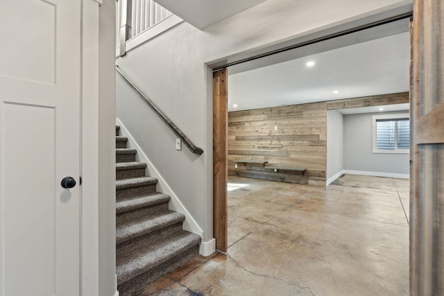 stairway featuring concrete floors and wood walls